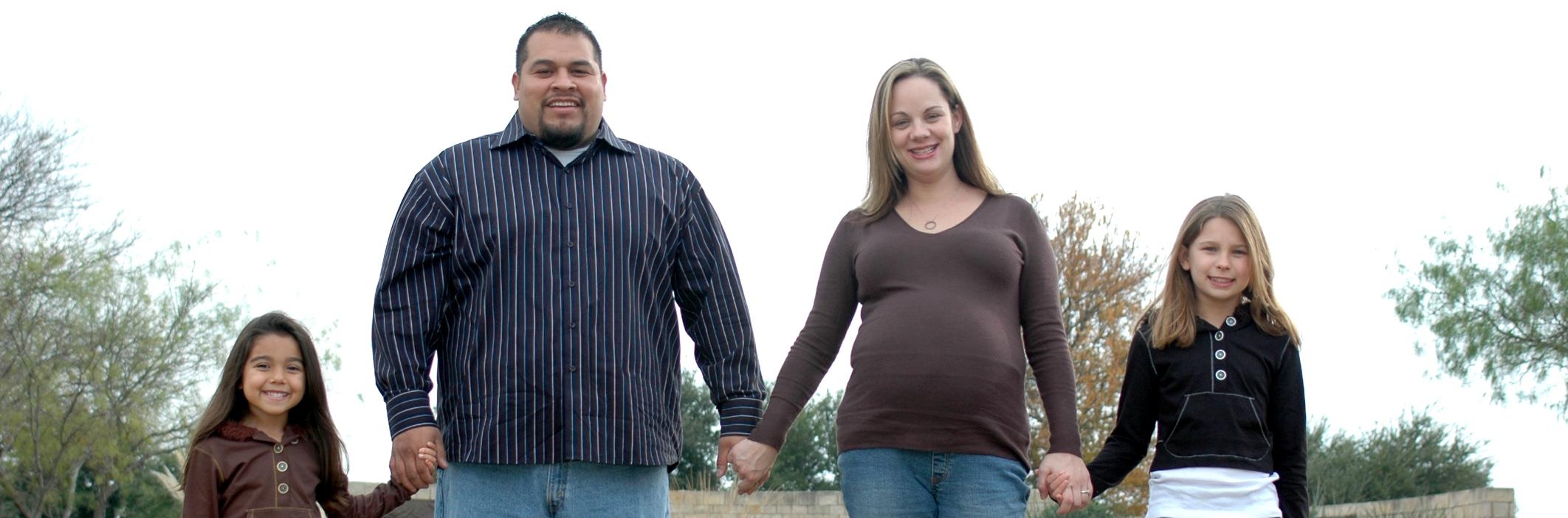 Image of mother and father holding hands of two young daughters